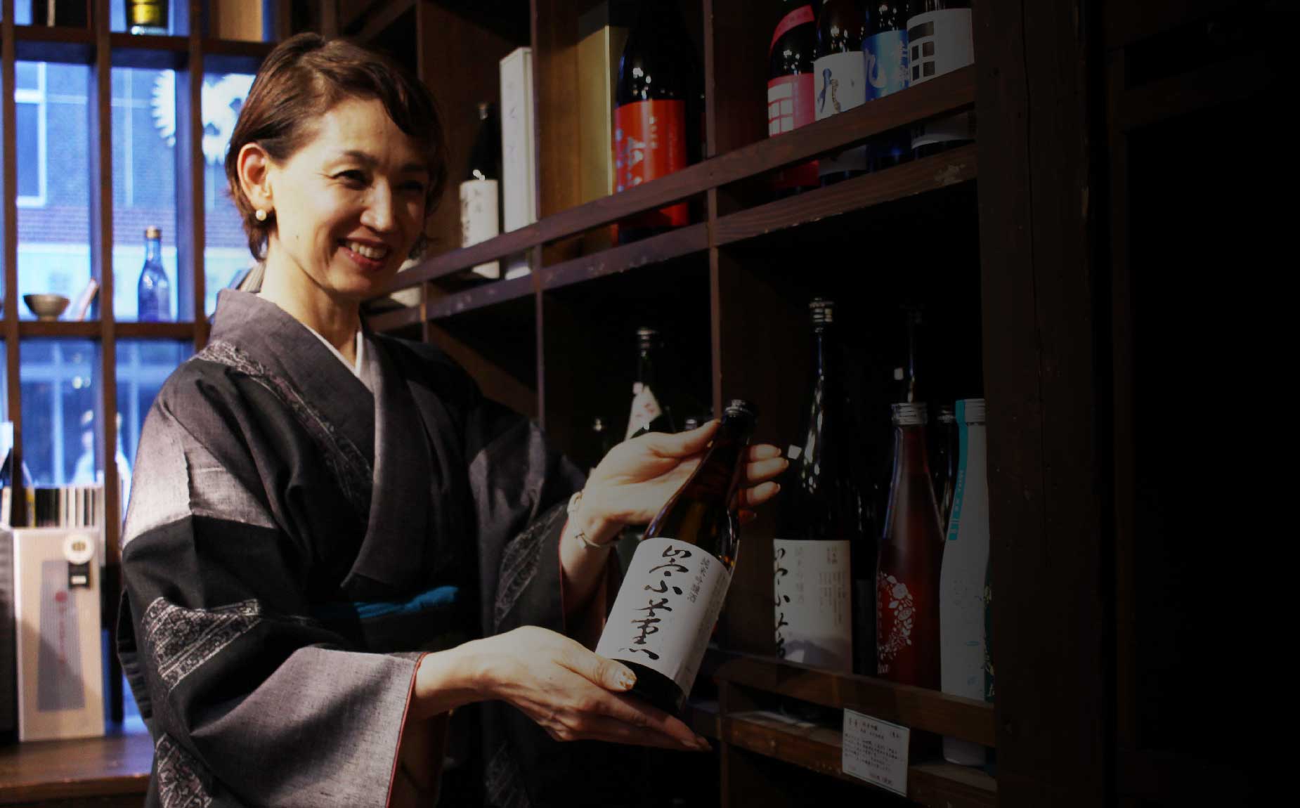 川上酒店の奥様が純米吟醸酒、崇薫をもった写真