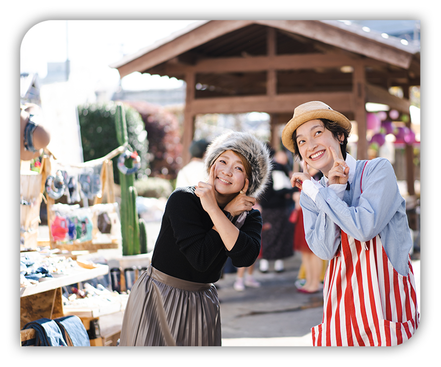 女性と男性がカメラ目線でマルシェを楽しむ様子の写真