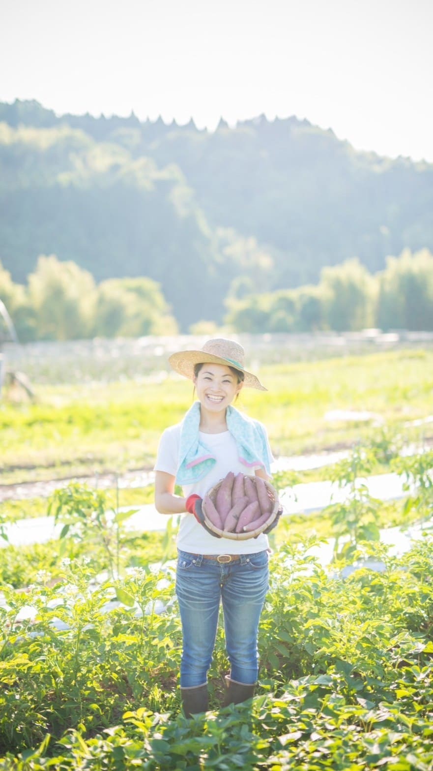 さつまいもを持って笑っている女性の写真
